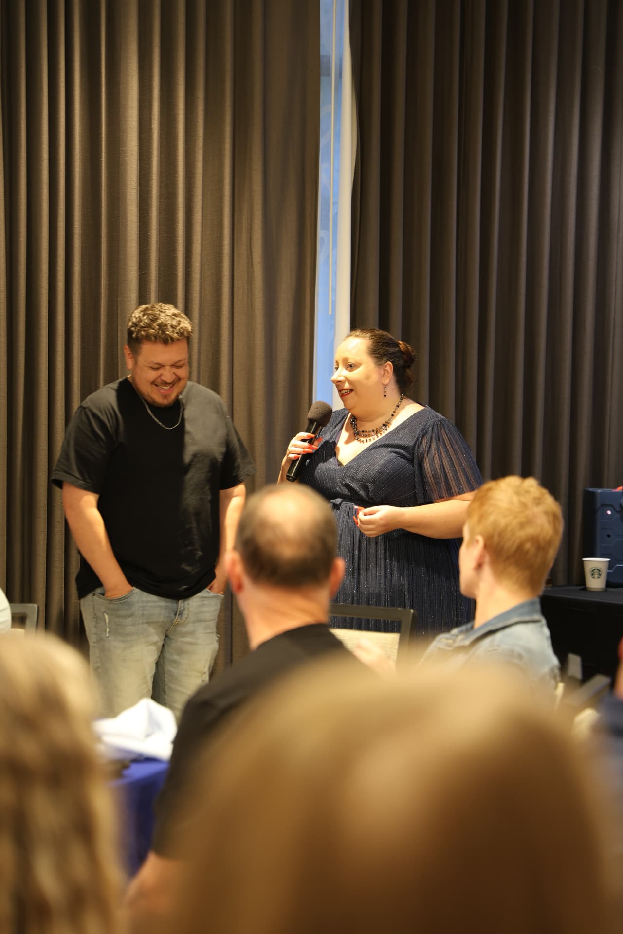 Joanna speaking with a microphone next to an agent on stage